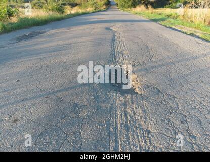 Asphalt road in poor condition with potholes and potholes Stock Photo