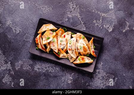 Fried dumplings served with green onions, sesame seeds and chili peppers, top view Stock Photo