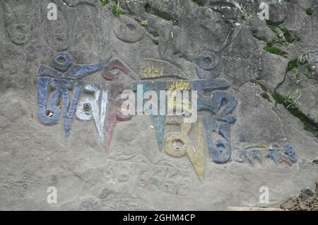 Om Mani Padme Hum (Buddhist mantra) written Tibetan script on rock in Rewalsar lake (Tso Pema), Himachal Pradesh, India Stock Photo