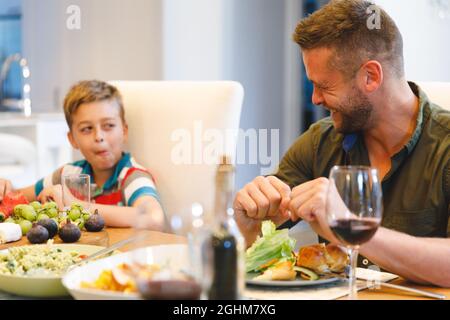 Happy caucasian father with son sitting at table and having dinner Stock Photo