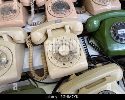 Composition of many old rotary telephones arranged on wooden shelves in light room Stock Photo