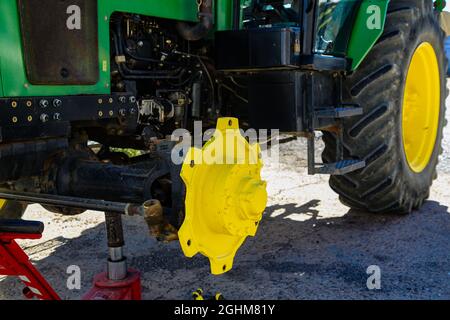 Green and yellow tractor without wheel to repair Stock Photo