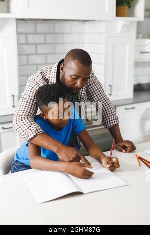 African american father and his son in kitchen, doing homework together Stock Photo