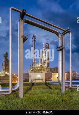 Construction with pipeline and Illuminated petrochemical production plant at twilight, Port of Antwerp. Stock Photo