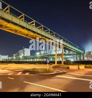 Scaffold with pipeline and Illuminated petrochemical production plant at nighttime, Port of Antwerp. Stock Photo