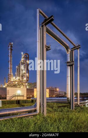 Construction with pipeline and Illuminated petrochemical production plant at twilight, Port of Antwerp. Stock Photo