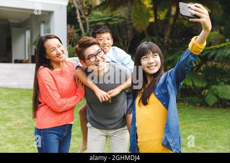 Happy asian parents, son and daughter smiling outdoors and taking selfie in garden Stock Photo