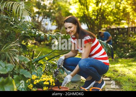 Smiling caucasian man and woman working in garden wearing gloves Stock Photo