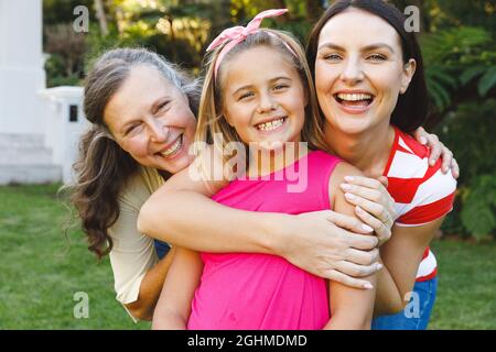 Portrait of smiling caucasian grandmother with adult daughter and granddaughter in garden Stock Photo
