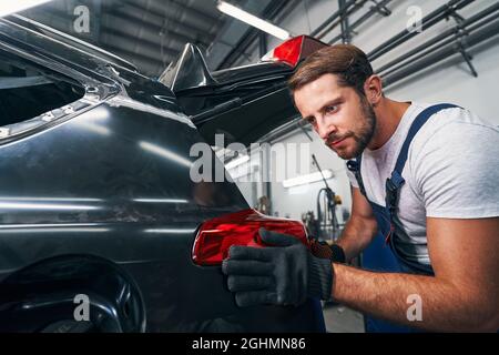 Tachnician is touching rear light of car Stock Photo
