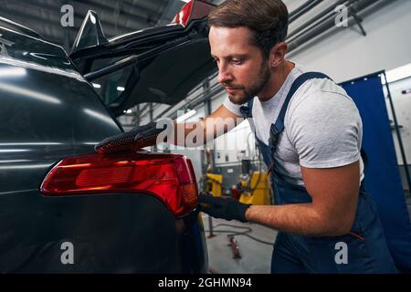 Male mechanic checking the level of car taillight Stock Photo