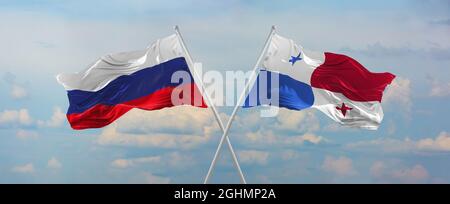 flags of Russia and Panama waving in the wind on flagpoles against sky with clouds on sunny day. Symbolizing relationship, dialog between two countrie Stock Photo