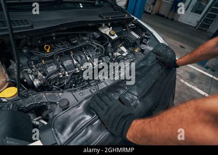 Person checking the condition of car engine under hood Stock Photo