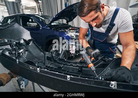 Car repair professional operating drill while working on engine Stock Photo