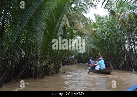 Tourists on a lagoon padding along mangrove forest by locals Stock Photo