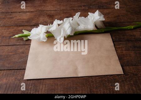 bouquet of white gladioli on a wooden table with an envelope in vintage style Stock Photo