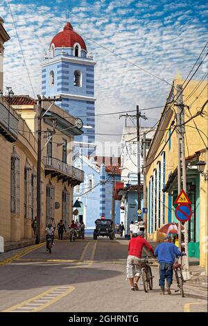 Street scene, Caribbean, people, Cubans, old houses from Spanish colonial times, in the back bell tower of the church Iglesia Parroquial Mayor del Stock Photo