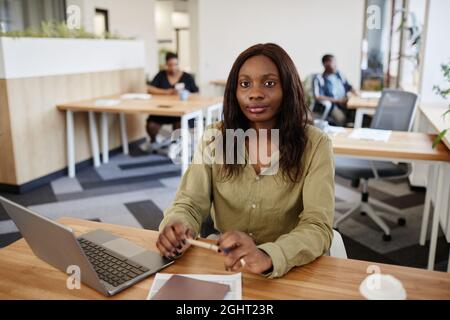 Portrait of serious pensive elegant businesswoman sitting at office desk with pen in hands Stock Photo