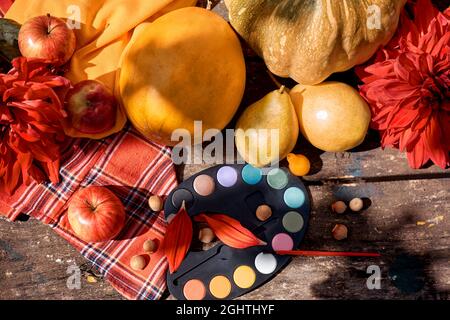 Autumn flat lay: yellow fruits, vegetables and bright paints with a brush, pumpkin, pears, apple and melon. Autumn still life with red georgine, moder Stock Photo