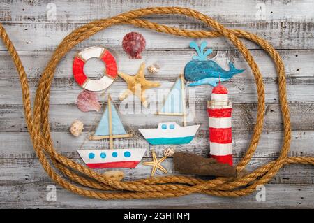 Cute set of kids handcrafted boats, fish, nautical attributes and more on rough vintage wooden background top view Stock Photo