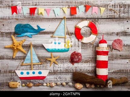 Cute set of kids handcrafted boats, fish, nautical attributes and more on rough vintage wooden background top view Stock Photo