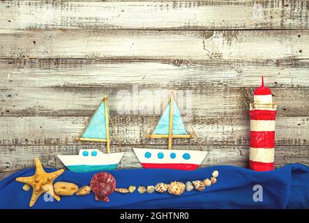 Cute set of kids handcrafted boats, fish, nautical attributes and more on rough vintage wooden background top view Stock Photo