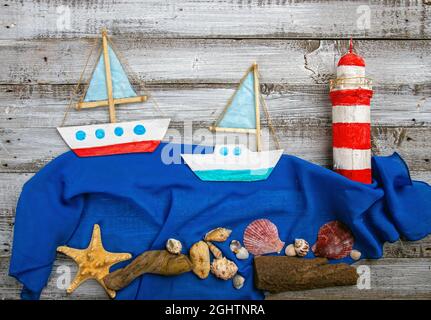 Cute set of kids handcrafted boats, fish, nautical attributes and more on rough vintage wooden background top view Stock Photo