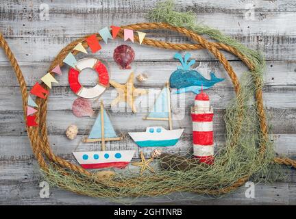 Cute set of kids handcrafted boats, fish, nautical attributes and more on rough vintage wooden background top view Stock Photo