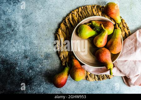 Overhead view of ripe organic pears in a ceramic bowl on a place mat with a napkin Stock Photo