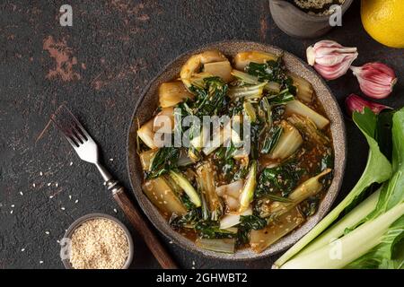 Bok choy vegetables stir fry with soy sauce and sesame seeds on dark background. Chinese cuisine. Top view. Healthy vegan food Stock Photo