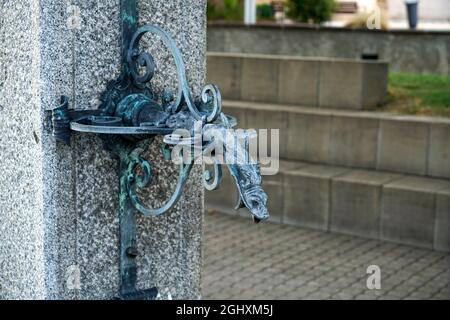 Closeup shot of a vintage snake-shape water mixer on a stone column outdoors Stock Photo