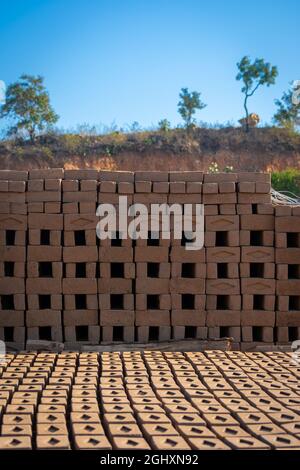 Hand made bricks from wet clay and mud are kept for drying before the burning process. Traditional production of clay bricks in India. Stock Photo