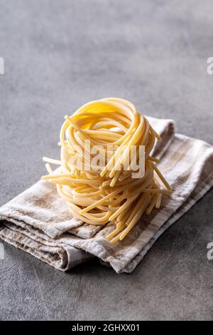 Italian pasta nest on napkin. Uncooked spaghetti nest on kitchen table. Stock Photo