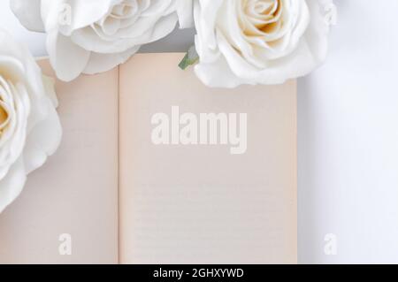 a book and white roses on the table, empty space for title Stock Photo