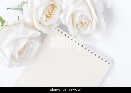 a book and white roses on the table, empty space for title Stock Photo