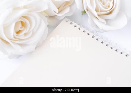 a book and white roses on the table, empty space for title Stock Photo