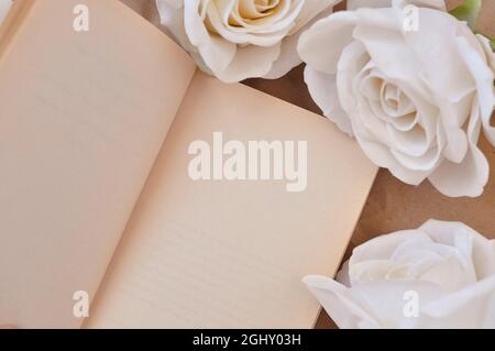 a book and white roses on the table, empty space for title Stock Photo