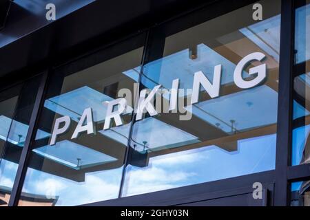Low angle view of large white letters spelling out Parking on a glass window of a building. Stock Photo