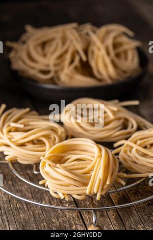 Italian pasta nest. Uncooked spaghetti nest on old wooden table. Stock Photo