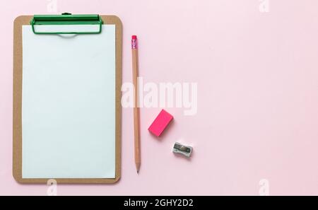 School supplies, student desk top view, Blank paper clipboard, pencil eraser and sharpener on pink background, copy space, template. Stock Photo