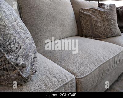 Close up view of several pillows piled on a light colored couch in a living room Stock Photo