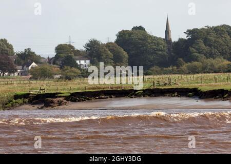 The Solway Bore travelling along the channel of the River Eden with Rockcliffe village in the background Stock Photo