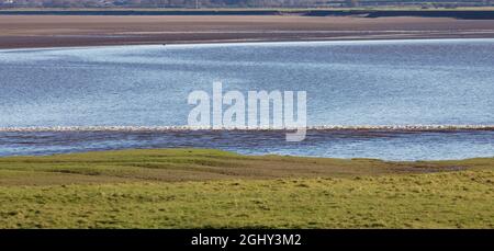 The Solway Bore heading inland up the low tide channel of the River Eden Stock Photo