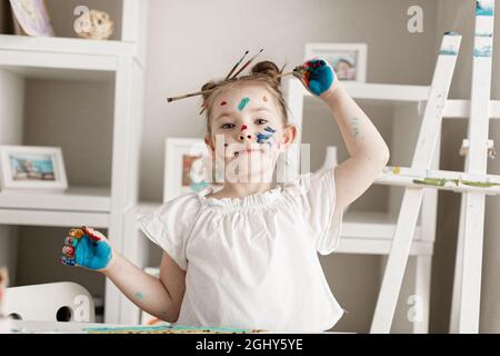 education, school, art and painitng concept - little student girl showing painted hands. High quality photo Stock Photo