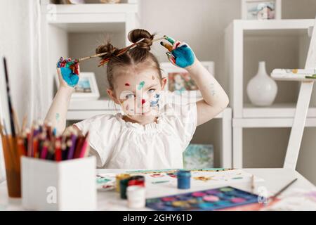 education, school, art and painitng concept - little student girl showing painted hands. High quality photo Stock Photo