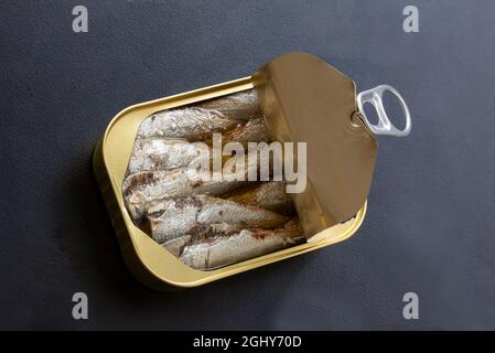 Open tin can of sardines with lid open and ring pull  on black background. Top view photo. Stock Photo