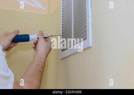 Removing air vent cover on wall with square but screw driver Stock Photo