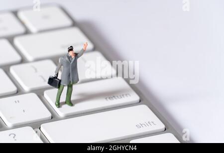 Miniature Male figure with hat and briefcase standing on Return Key Stock Photo