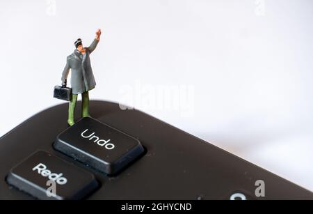 Miniature man with With Left Arm in the Air next to Undo Key Stock Photo