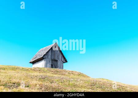 Picturesque autumn meadow with old wooden house and blue sky in the Carpathian mountains, Ukraine. Landscape photography Stock Photo